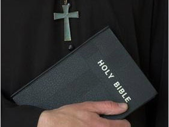 priest-holding-bible-with-crucifix